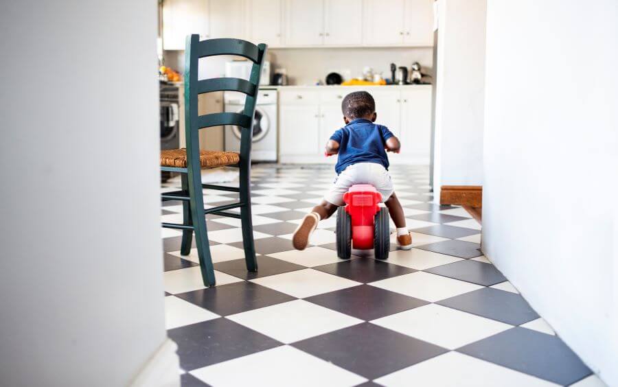 Small boy riding a bike on the tiled floor kitchen image